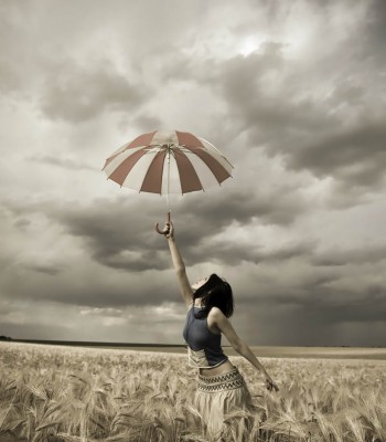 Girl with umbrella in rainy day at wheat field